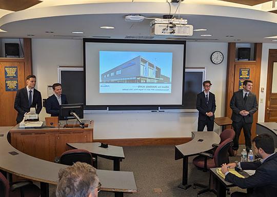 four young men in front of a screen giving a presentation